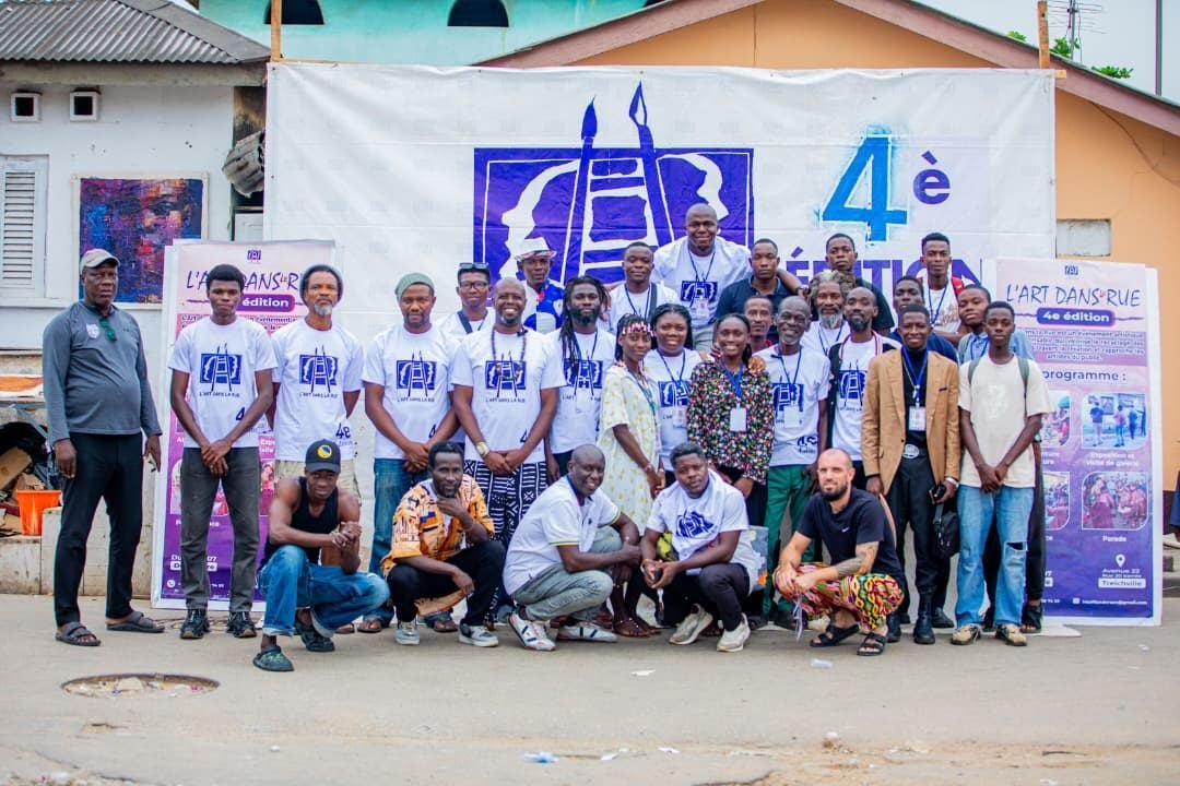 Photo de groupe des artistes et bénévoles de la 4e édition devant la bannière de l'événement